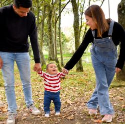 A joyful family enjoys a walk under lush green trees in the park.