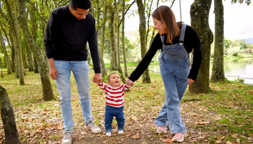 A joyful family enjoys a walk under lush green trees in the park.